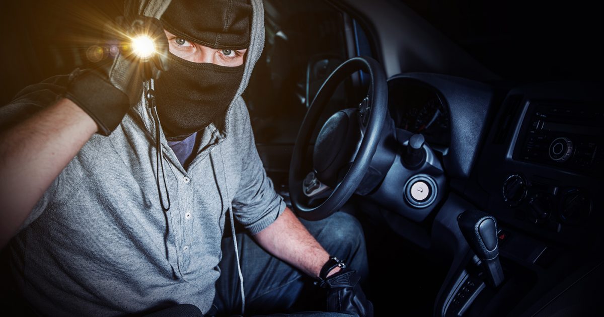 Ladrón dentro de un auto, con linterna.