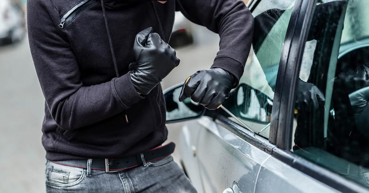 Sujeto con guantes negros tratando de forzar un vehículo, en el contexto de algunos consejos para evitar que roben tu auto.