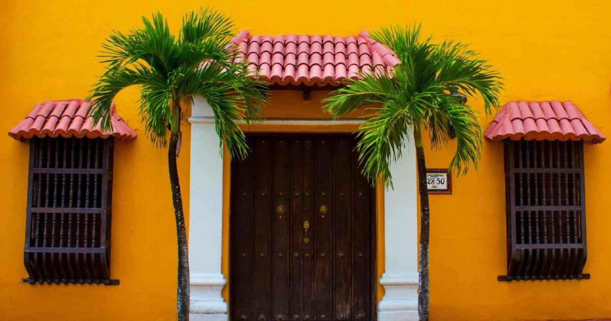 foto de una casa antigua con dos palmeras en la entrada
