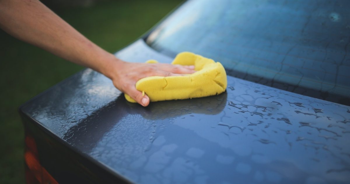 foto de una persona lavando con una esponja el auto