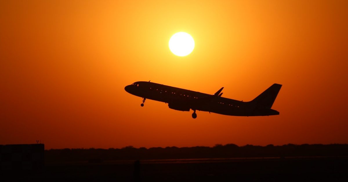 foto de un avión despegando con el fondo de un sol que ilumina toda la fotografía