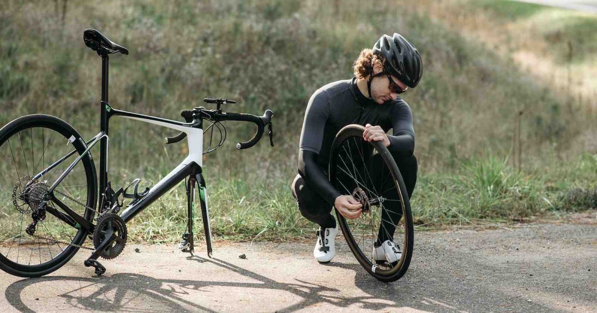 foto de una persona reparando su bicicleta en el camino
