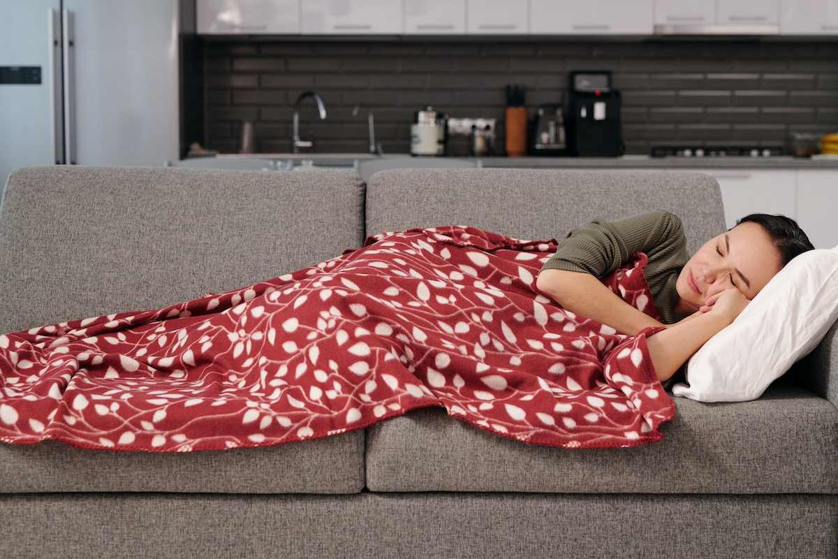 foto de una persona durmiendo en un sofá con una manta