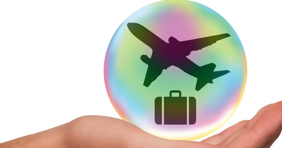foto de una burbuja con el símbolo de un avión y una maleta, los cuales están sobre una mano