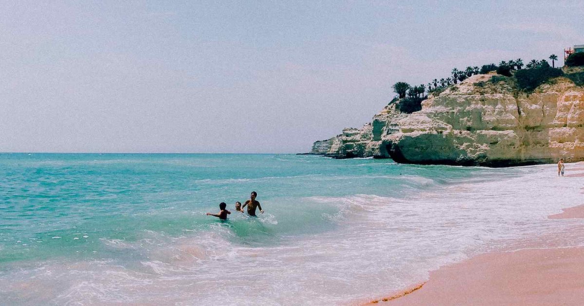 foto de la orilla de una playa con 2 personas bañándose
